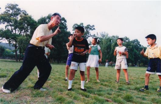 5.王全忠老师虽然已到耄耋之年，但对山东快书的感情越来越深，一直致力于该项目的传承、展示、展演工作。此图是2016年6月30日，王全忠老师在牧野公园辅导王家兴、王鑫诚等小学员们进行山东快书表演训练。